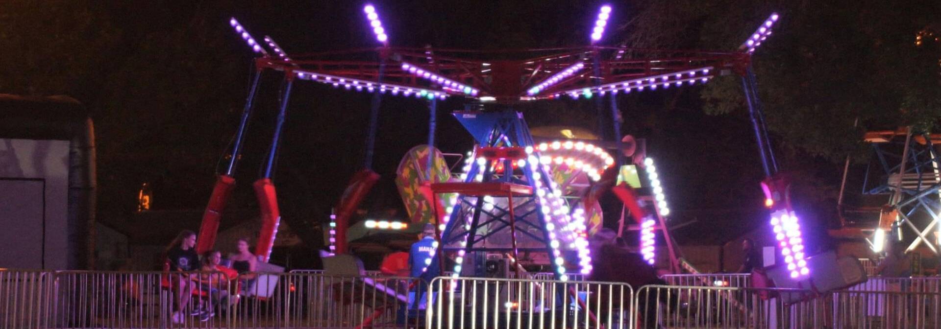 Carnival ride lit up at night at the Madison County Fairgrounds